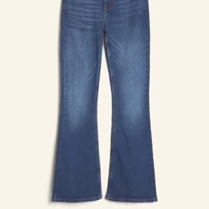 Blå low flare jeans - Säljer ett par blå jeans med låg midja och utsvängda ben, så kallad flare-modell. Jeansen har klassisk femficksdesign och dragkedja framtill. Perfekta för dig som gillar retrovibbar och vill ha en snygg siluett.