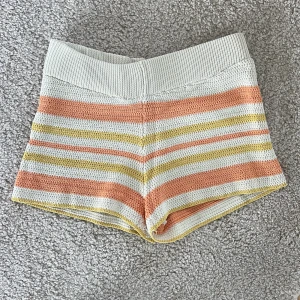 Randiga stickade shorts i pastellfärger - Superfina stickade shorts med bred resår i midjan. Randigt mönster i beige , ljusgul och persikoorange. Perfekta för varma dagar eller som mysplagg hemma. Mjukt och stretchigt material.