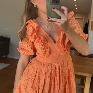 Orange klänning volang  - Superfin orange klänning med v-ringning, volangdetaljer och broderat mönster. 