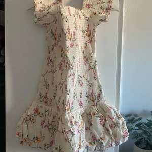 Blommig offshoulder klänning med volang - Säljer denna populära blommiga klänningen från hm. Endast provad, inte använd då den inte passade