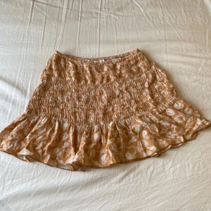 Orange kortkjol med volang och snäck mönster - Säljer denna super söta orangea/rostbruna kortkjolen med somrigt snäckmönster! Strl S💗Den är i 100% viskos och riktigt skön🌺 