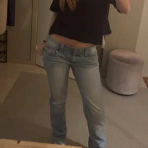 Ljusblå jeansbyxor med dubbla knappar - Säljer ett par ljusblå jeansbyxor med snygg tvätt och dubbla knappar i midjan. Klassisk femficksmodell och raka ben. Perfekta för en avslappnad stil. Bootcut!!