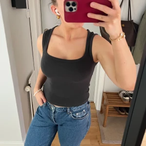 Svart croppad linnetopp från Gina Tricot - Säljer en svart croppad linnetopp från Gina Tricot. Toppen har breda axelband och en fyrkantig ringning. Perfekt att matcha med jeans eller kjol för en enkel och stilren look.