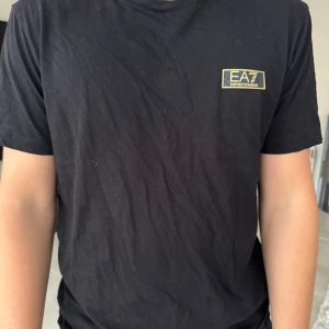 Svart t-shirt från EA7 Emporio Armani - Riktigt skön och luftig tröja från EA7, svart T-shirt med Armani går aldrig fel. Står tyvär ingen storlek men skulle gissa på M. Därav sälja den för 300 bara 