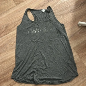 Grått linne från Gina Tricot - Säljer ett grått linne från Gina Tricot i storlek M. Linnet har en lös passform och är ärmlöst med brottarrygg. Perfekt för varma dagar eller till träning.