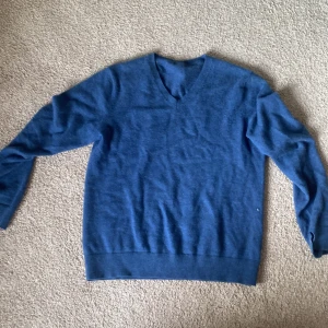 Blå v-ringad tröja - Mysig blå v-ringad tröja i mjukt material. Perfekt för lager-på-lager och passar till både jeans och kjol. Långärmad och enkel design som funkar året runt.