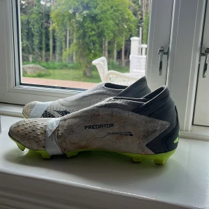 Adidas Predator fotbollsskor i vitt och neongult - Säljer mina fotbollsskor dem är rätt så söndriga men vill bara bli av med dem rekommenderar att köpa dem om du bara vill ha några som kanske ett par extra skor eller när du ska lira lite med grabbarna
