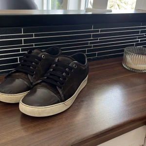 Bruna sneakers från Lanvin - Söker byte! 6-7/10 bruna ingår box men ingen dustbag. Passar till det mesta. Storlek 43 men passar 44. Lite trasig där fram på skon.