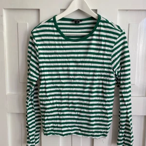 Grön- och vitrandig långärmad från Monki - Säljer en långärmad tröja från Monki i grönt och vitt med klassiskt randigt mönster. Älskar den men säljer då den ej passar längre 🍏