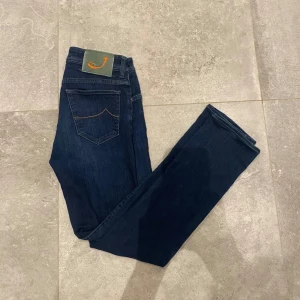 Mörkblå jeans från Jacob Cohën - Snygga mörkblå jeans från Jacob Cohën med klassisk femficksdesign och orangea sömmar. Tillverkade av exklusiva material med italienskt hantverk. Perfekta för en stilren look. Använda ett par gånger  Storlek 30. Hör av dig vid fler frågor 🪐🪐 pris kan diskuteras!!!!