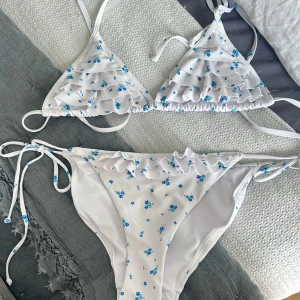 Vit blommig bikini med volang och knyt - Skit söt bikini i fint skick, tyvärr är lapparna borta men skulle säga att den passar S och Xs🩵🩵