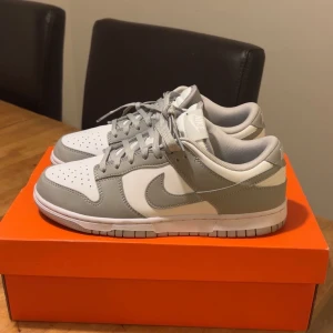 Nike Dunk Low i grått och vitt - Säljer ett par fräscha Nike Dunk Low i grått och vitt. Använda 1 gång endast så i princip helt nya. Säljes för att jag behöver pengar och för att dom inte används. Köptes på Zalando för längesedan. Vid frågor eller fler bilder så är det bara att skriva!
