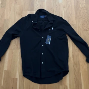 Svart Ralph Lauren Skjorta - Helt Ny Ralph lauren skjorta i storlek S , den är inte använd har bara testat den på så den är helt ny. Tveka inte om frågor