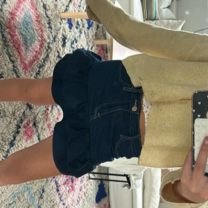 Mörkblå volangkjol i jeans - Supersöt mörkblå jeanskjol med volangkant och klassiska fickor både fram och bak. Kjolen har en kort passform och stängs med knapp och dragkedja framtill. Perfekt för dig som gillar denim och vill ha en lekfull twist på din outfit. Jag har sytt den själv men den är väldigt bra sydd! Priset kan diskuteras vid snabb köp💕