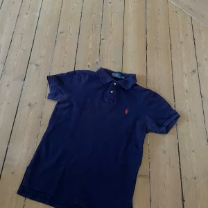 Ralph Lauren piké  - Klassisk marinblå pikétröja från Ralph Lauren. Storlek M, men modellen är smal i passformen – sitter som en tight M eller som en S (muscle fit). Använd, i okej skick. Inga hål eller fläckar. Perfekt för en tidlös och uppklädd vardagsstil.