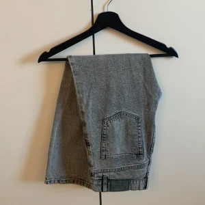 Gråa jeans från Grunt - Säljer ett par grå jeans från Grunt med klassisk femficksdesign och knappgylf. Jeansen har raka ben och är tillverkade i ett slitstarkt denimtyg. Perfekta för en avslappnad och stilren look.