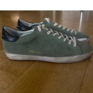 Gröna sneakers från Golden Goose - Snygga gröna sneakers från Golden Goose med ovandel i mocka och svarta detaljer vid hälen. Skorna har vita snören och en platt sula. Perfekta för dig som gillar en stilren och avslappnad look.