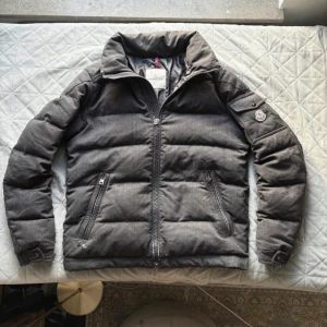  Moncler jacka - Säljer en grå moncler pufferjacka  med hög krage och dragkedja framtill. Skickat är inte det bästa så kom med prisförslag då jag vill bli av med jackan. Hör av dig om du har några funderingar 
