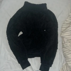 Svart fluffig tröja från stadium  - Mysig svart fluffig tröja från stadium i storlek XS. Tröjan har en liten krage och långa ärmar med breda muddar. Det är lika fluffigt inuti som utanpå♥️