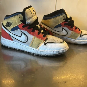 Nike Air Jordans i färgglad patchwork - Säljer ett par unika Nike Air Jordans med patchwork-design i blått, rött, beige, svart och vitt. Skorna har svart snörning, rund tå och platt sula. Fint skick! 