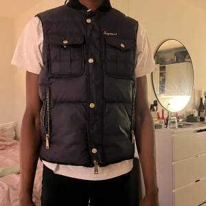 Dsquared väst - Säljer en svart dunväst från Dsquared. Västen har två stora bröstfickor med lock och knapp, samt hög krage.