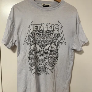  Metallica t-shirt från Pull&Bear - Oversized t-shirt från Pull&Bear med Metallica-tryck framtill. Stort svart tryck med dödskallar och fjäril, klassisk rund hals och korta ärmar. Perfekt för dig som gillar bandmerch och vill ha en cool stil. Storleken är XS, men den passar bekvämt som M.