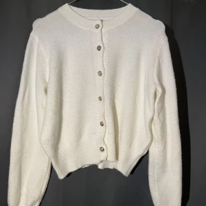 Vit stickad kofta med knappar - Mysig vit stickad kofta med långa ärmar och dekorativa knappar framtill. Perfekt för lager-på-lager-stil. Enkel och stilren design som passar till många outfits. Storlek S men passar som M!💗