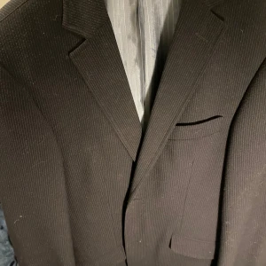 Mörkbrun randig kavaj från Luigi Morini - Säljer en klassisk mörkblå kavaj från Luigi Morini med diskreta ränder. Kavajen har två framfickor, bröstficka och knappar framtill. Perfekt för dig som vill ha en stilren och tidlös look. Passar suveränt till skolavslutning😍