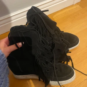 Svarta klackar med fransar - Säljer ett par svarta klackar med vita sulor och coola fransdetaljer längs sidorna. 