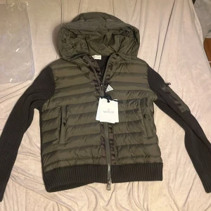 Moncler cardigan  - Hej säljer nu min Moncler cardigan som är i väldigt fint skick och jag har varit försiktig med den och bara använt den sällan och säljer den nu för den är ut ur säsong så bra pris för den är äkta.  Ända nackdelen är att det finns en liten färgfläck på luvan som ni ser på bilden det är därför den är så billig.Pris ej hugget i sten så var inte rädd att buda 