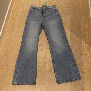 Blå wide high waist jeans från H&M Divided - Säljer ett par blå jeans från H&M Divided med wide fit och hög midja. Klassisk femficksmodell med raka, vida ben och knappgylf. Perfekta för en avslappnad och trendig look. Prislappen är på och dem är helt oanvändbara.