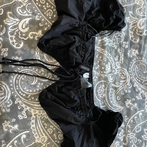 Svart topp från H&M Divided - Snygg svart topp från H&M Divided med knytband. Perfekt till sommaren och väldigt snygg. Kommer inte till användning längre därav säljer jag.💗💗