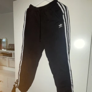 Svarta träningsbyxor från Adidas - Snygga svarta träningsbyxor/mjukisar i storlek S från Adidas. Byxorna har en elastisk midja med snörning 