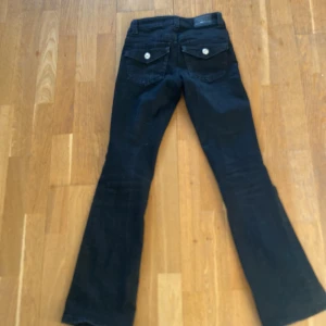 Svarta jeans från Gina tricot - Snygga svarta jeans från Perfect Jeans med bootcut-stil. De har en klassisk femficksdesign och knappar bak. Perfekta för en stilren look.
