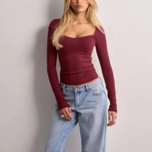 Vinröd långärmad topp - Säljer en vinröd långärmad topp med en djup, rundad halsringning. Perfekt för både vardag och festliga tillfällen, använd få gånger 