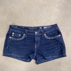 Mörkblå missme jeansshorts - Snygga mörkblå jeansshorts från Miss Me med broderade detaljer på fickorna.           Midjemått tvärs över: 42cm                                 Längd: 28cm 