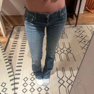 Blå jeans med broderade detaljer - Snygga blå jeans med broderade mönster på bakfickorna och dekorativa nitar. De har en låg midja och en bootcut-stil som ger en klassisk look. Perfekta för dig som vill ha något unikt i garderoben. Jag har sytt vi midjan men det är bara att klippa up om dem är för små är supper lätt 