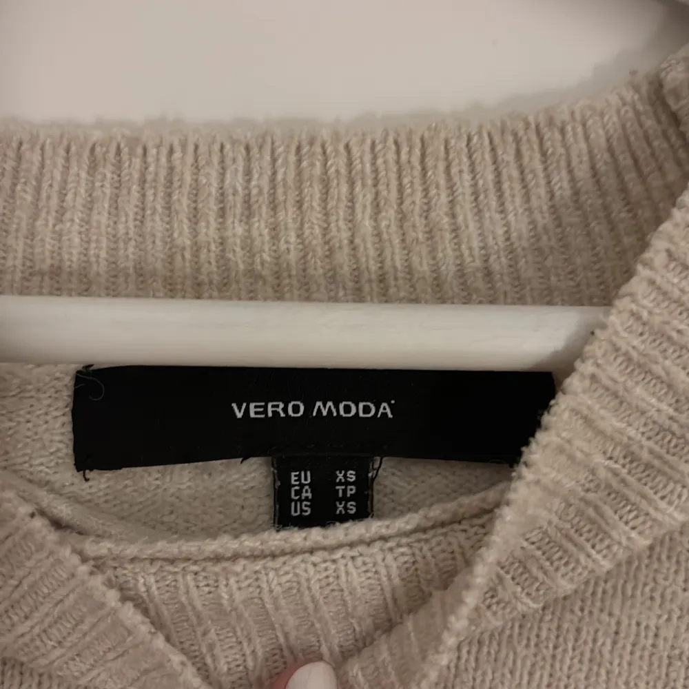 Säljer en mysig beige stickad tröja från Vero Moda. Tröjan har en klassisk design med långa ärmar och ribbade muddar vid ärmslut och nederkant. Perfekt för kyliga dagar!. Neuletakit & Villapaidat.