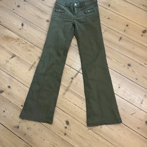 Olivgröna byxor från H&M Divided - Snygga och coola olivgröna byxor från H&M Divided som är bootcut. Byxorna har två framfickor med knappar och en klassisk dragkedja. Perfekta för lite varmare väder! 