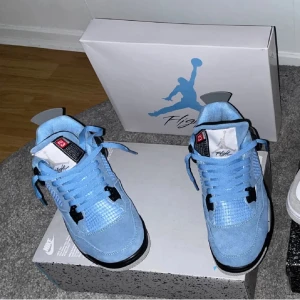 Nike Air Jordans i ljusblå mocka - Snygga Nike Air Jordans i ljusblå mocka med svarta och grå detaljer. Skorna har snörning och en ikonisk Jumpman-logga på hälen. Perfekta för dig som vill ha en stilren och sportig look.