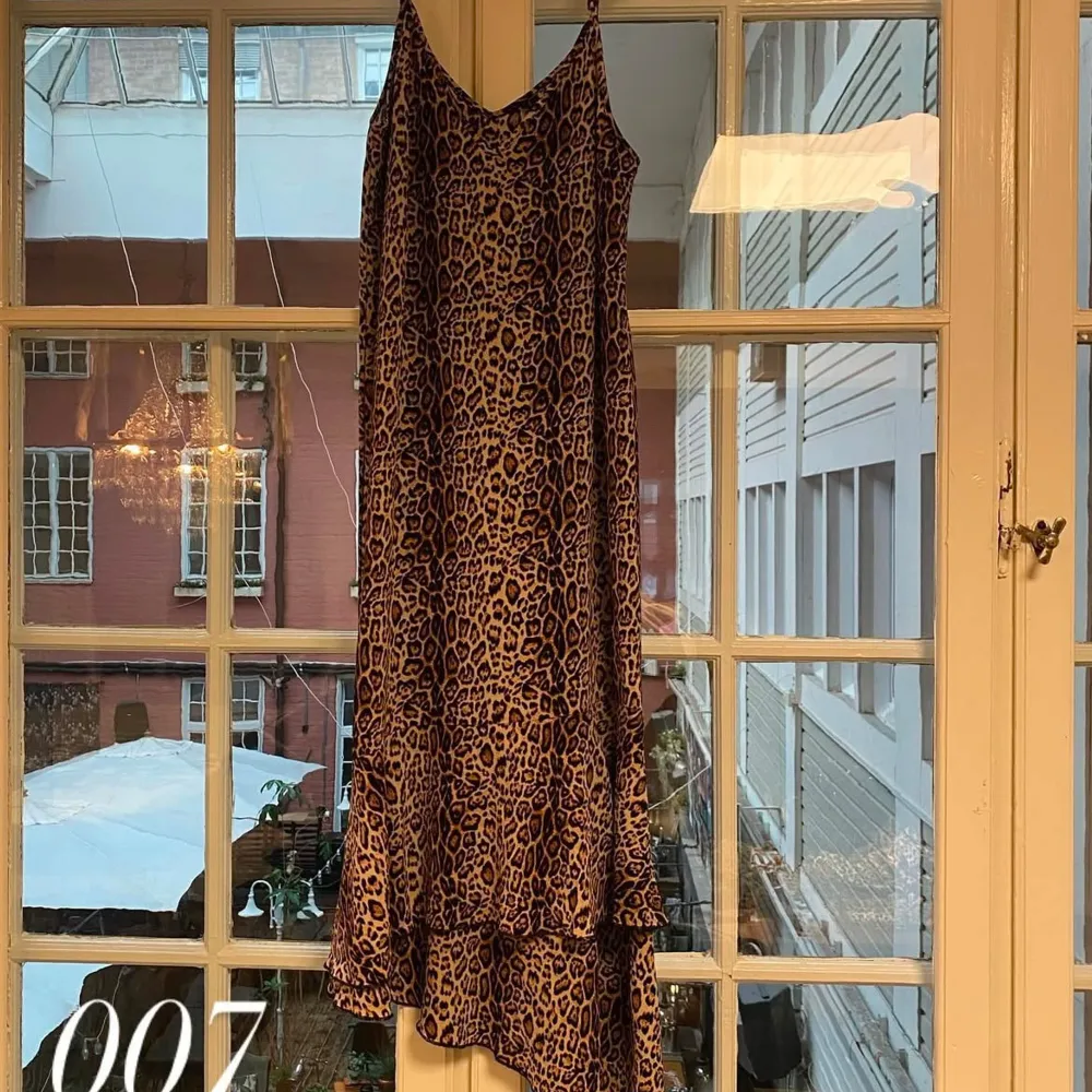 Snygg leopardmönstrad klänning med volangdetaljer. Klänningen har en v-ringad hals och är ärmlös, vilket ger en chic och trendig look. Perfekt för att sticka ut på festen!💕🐆. Mekot.