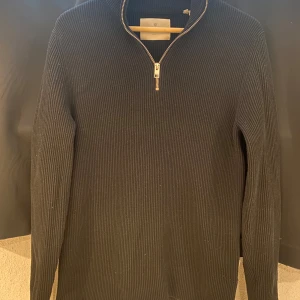 Svart half-zip tröja från Jack and Jones premium - Snygg svart half zip tröja från Jack and jones premium. Perfekt för kyligare dagar och ger en stilren look. Passar både till jeans och mer uppklädda tillfällen. Har haft den i cirka ett år och den är väld använd. Den är i bra skick med några tecken på användning!