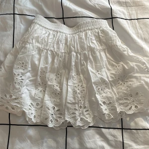 Vit kjol från Zara - Säljer en söt vit kjol från Zara med broderade blommor och inbyggda shorts!
