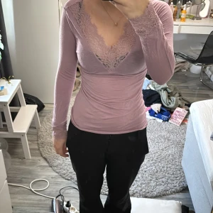 Rosa långärmad topp med spetsdetaljer - Säljer en elegant rosa långärmad topp från Intimissimi. Toppen har vacker spets vid halsringningen och är perfekt för en stilren look. Materialet är mjukt och bekvämt, vilket gör den idealisk för både vardag och speciella tillfällen. Passa på att köpa denna fina topp! 💖