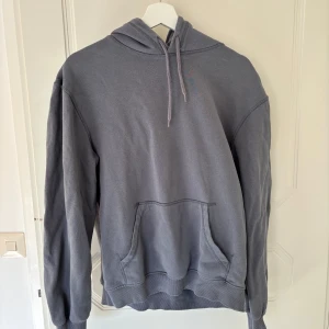 Grå hoodie från H&M - Säljer en grå hoodie från H&M. Den har en klassisk design med en stor ficka framtill och justerbar huva. 