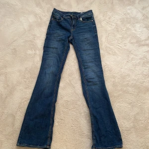 Blå bootcut jeans från Vero Moda - Snygga blå bootcut jeans från Vero Moda med klassisk femficksdesign och dragkedja med fickor där bak. Perfekta för en avslappnad stil med en touch av retro. Tillverkade i slitstarkt denim. Dom är mid waist. Hör gärna av er om ni vill ha fler bilder eller har frågor 💙💙💙