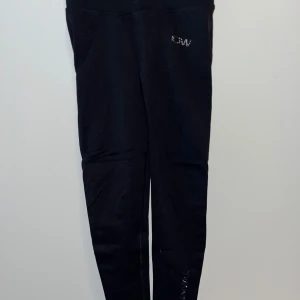 Svarta leggings från Röhnisch - Snygga svarta leggings från Röhnisch med en diskret logga på höften. Perfekta för träning eller en avslappnad dag. De har en tight passform och är tillverkade i ett stretchigt material för bästa komfort.