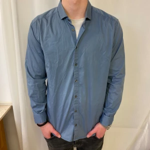  Tiger of Sweden skjorta  - Snygg blå skjorta från Tiger of Sweden i slim fit. Skjortan har långa ärmar och knappar framtill. Perfekt för en stilren look.