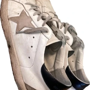 Golden gose skor - Snygga vita sneakers med en distinkt stjärndetalj på sidan. Har lite defekter på sig. Skorna har snörning och en klassisk design som passar perfekt för en avslappnad stil. Perfekta för dig som gillar en stilren look med en twist. Storlek 44 