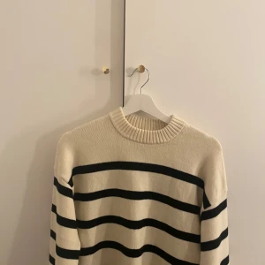Randig tröja från H&M - Säljer en stilren randig tröja från H&M i beige och svart. Tröjan har en klassisk rund hals och långa ärmar, perfekt för en avslappnad look. Materialet är mjukt och bekvämt, vilket gör den idealisk för kyligare dagar.